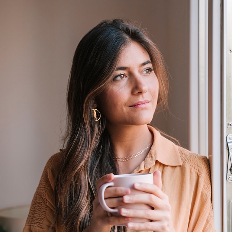 Woman with coffee cup looking out of window